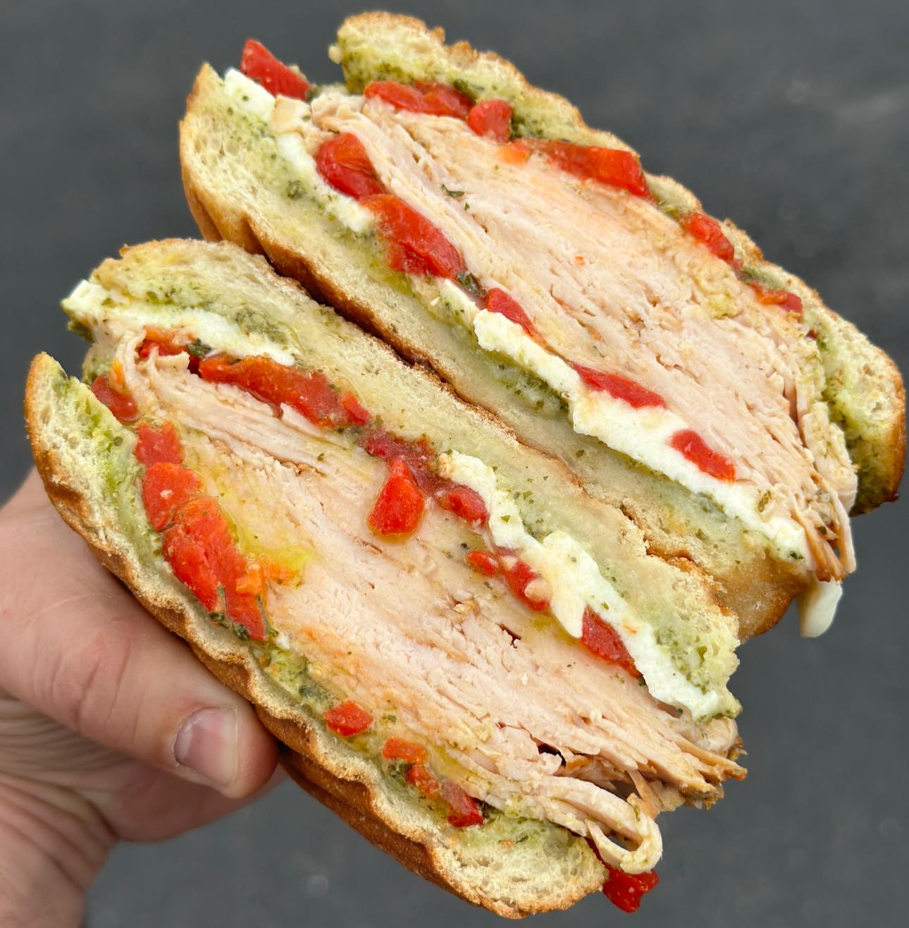 Sliced turkey sandwich with tomato and pesto seasoning